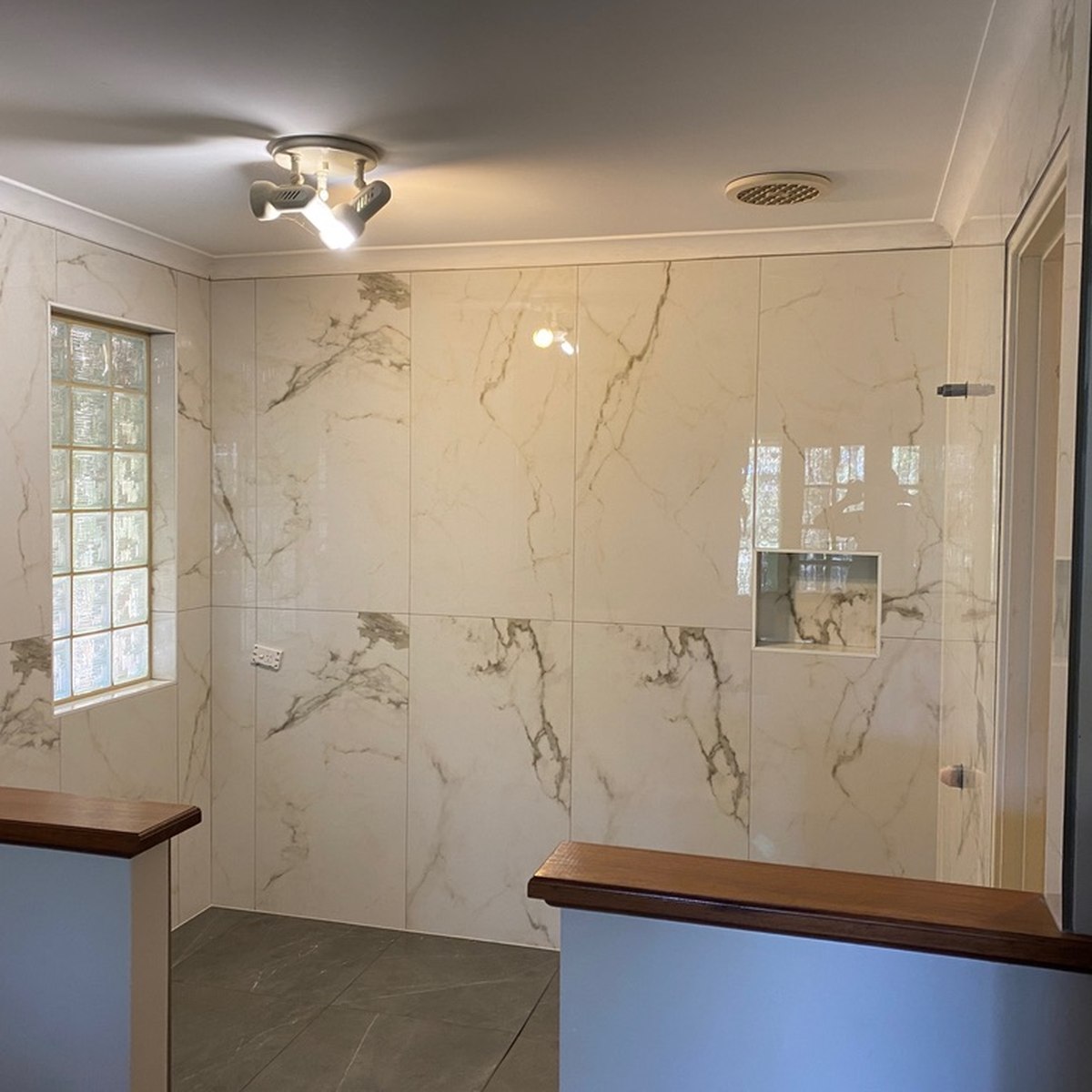 The same bathroom finished with large-format marble-look wall tiling and a frameless glass shower by Rayan Tiling Services Perth