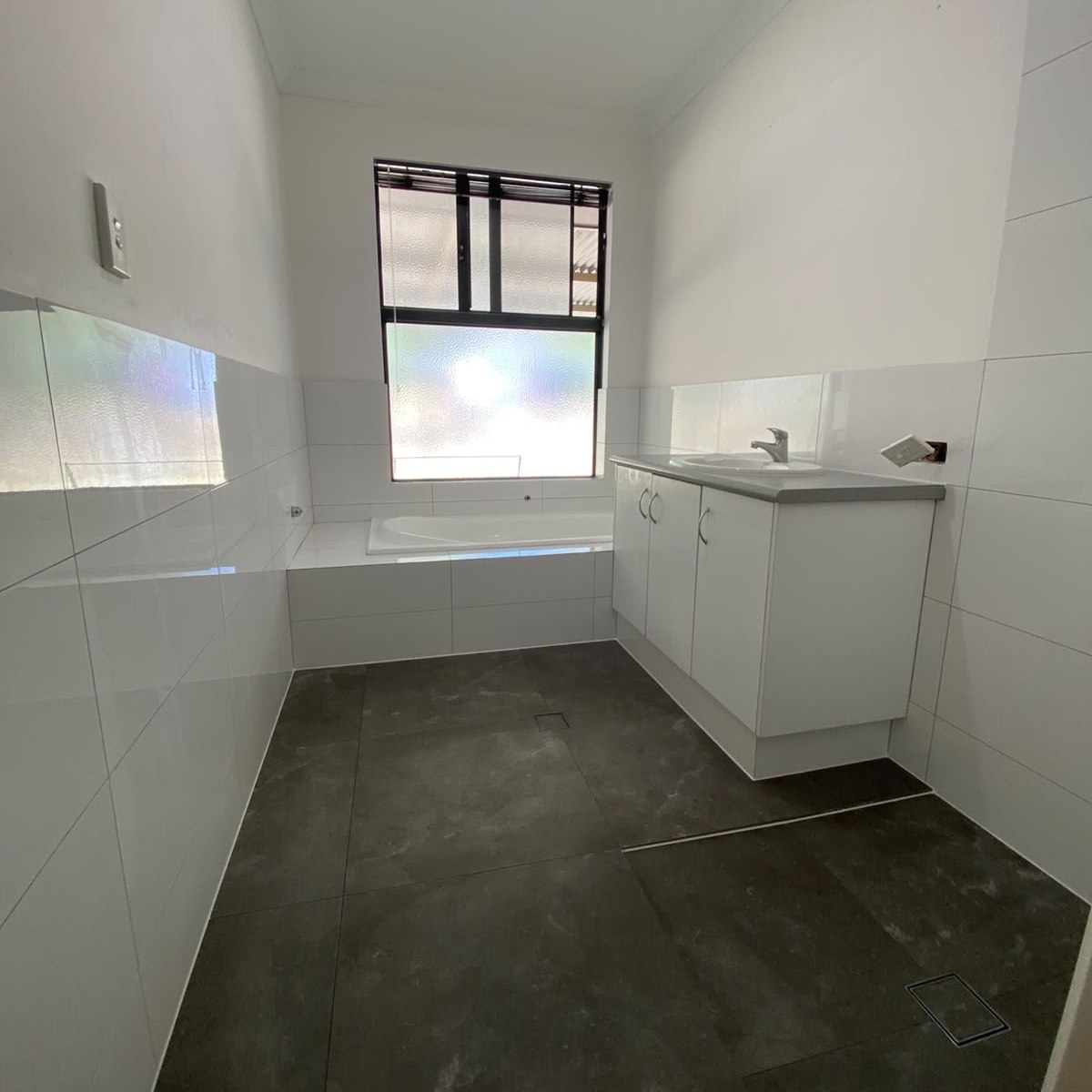 The same bathroom finished with white gloss wall tiling and large-format charcoal floor tiles by Rayan Tiling Services Perth