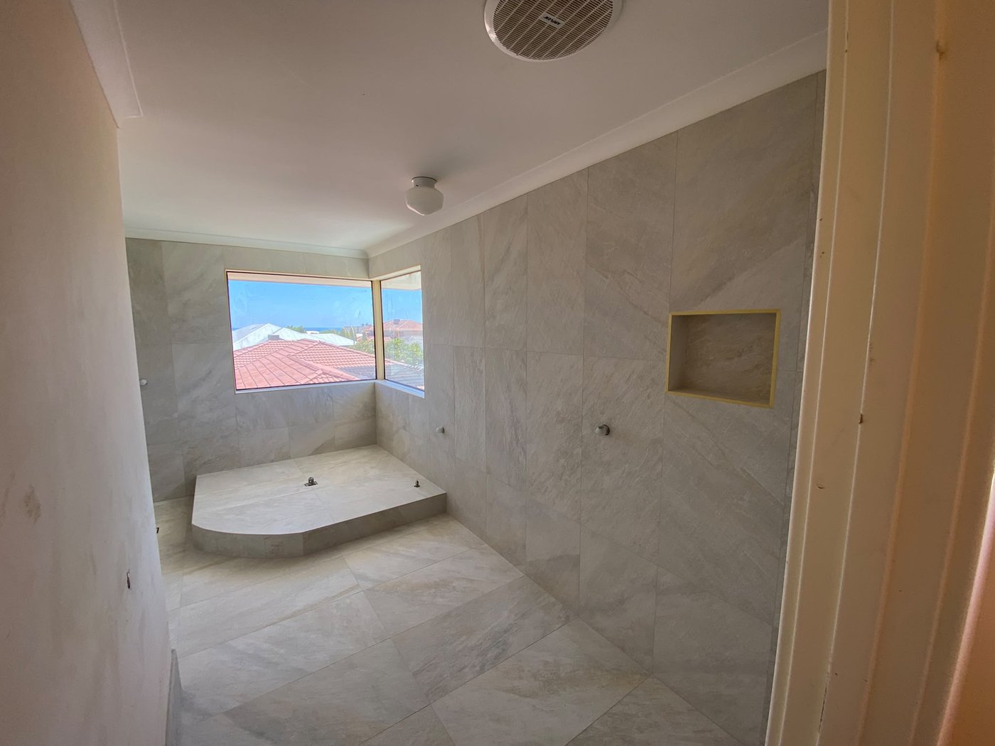 Marble-look ensuite with raised tiled platform and shelf niche in Perth
