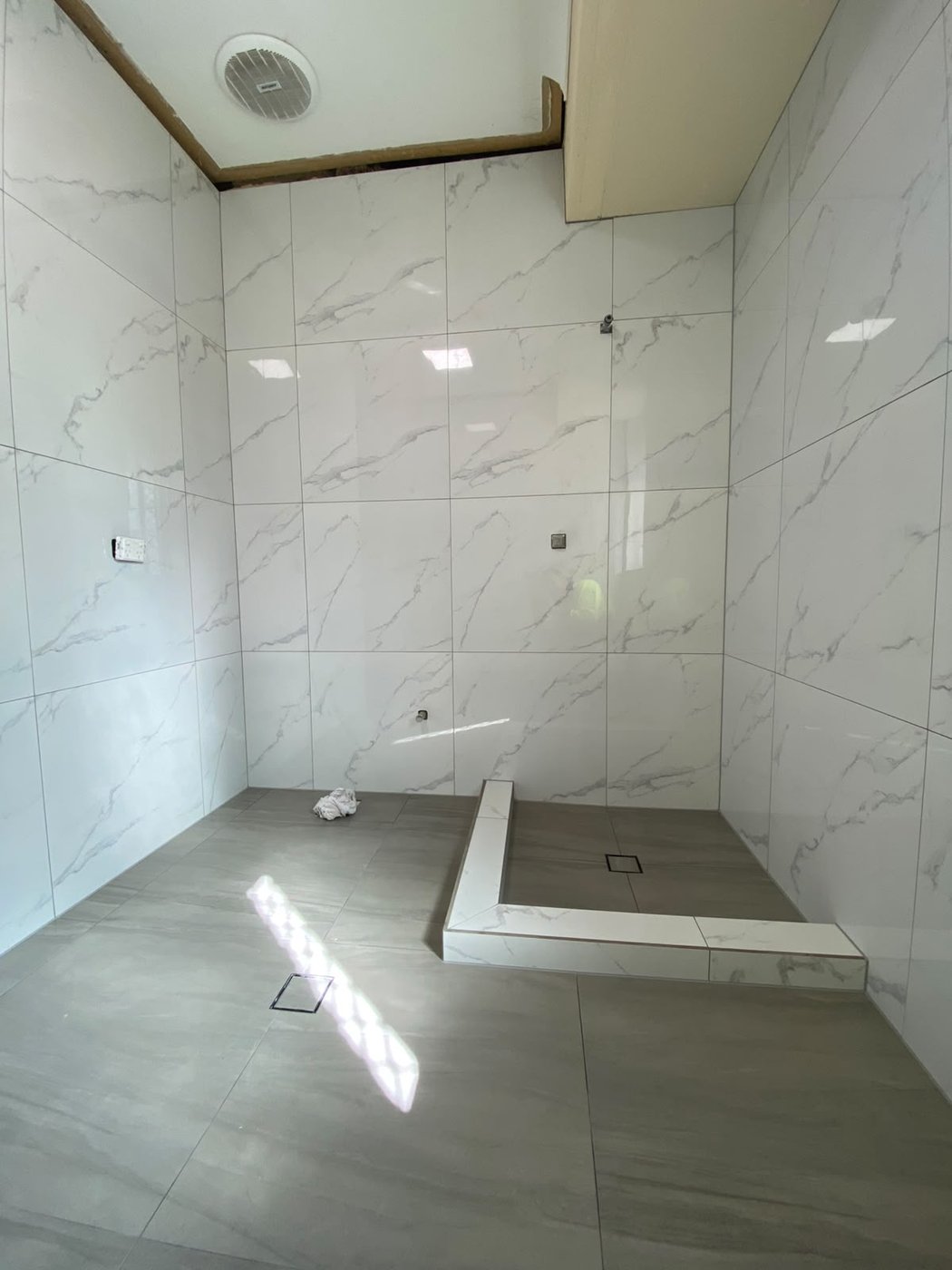 White marble-look walk-in shower with hobbed base and grey floor tiling in Perth