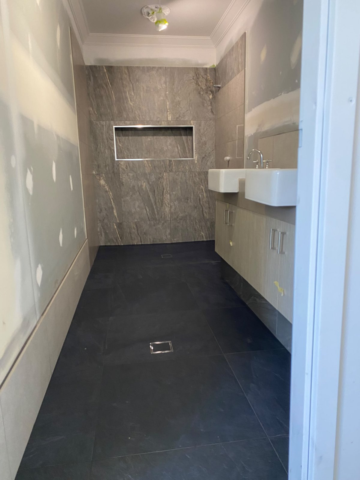 Dramatic grey stone-look feature wall with charcoal floor tiling in a Perth bathroom